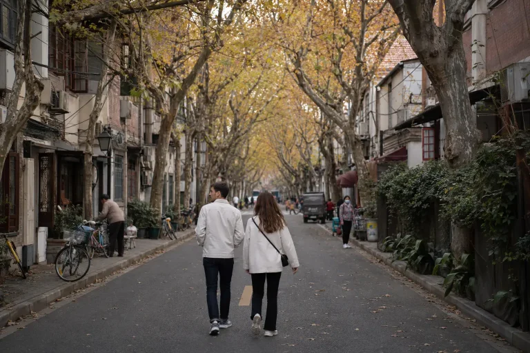 Travelers walking beneath autumn plane trees during the best time to visit Shanghai