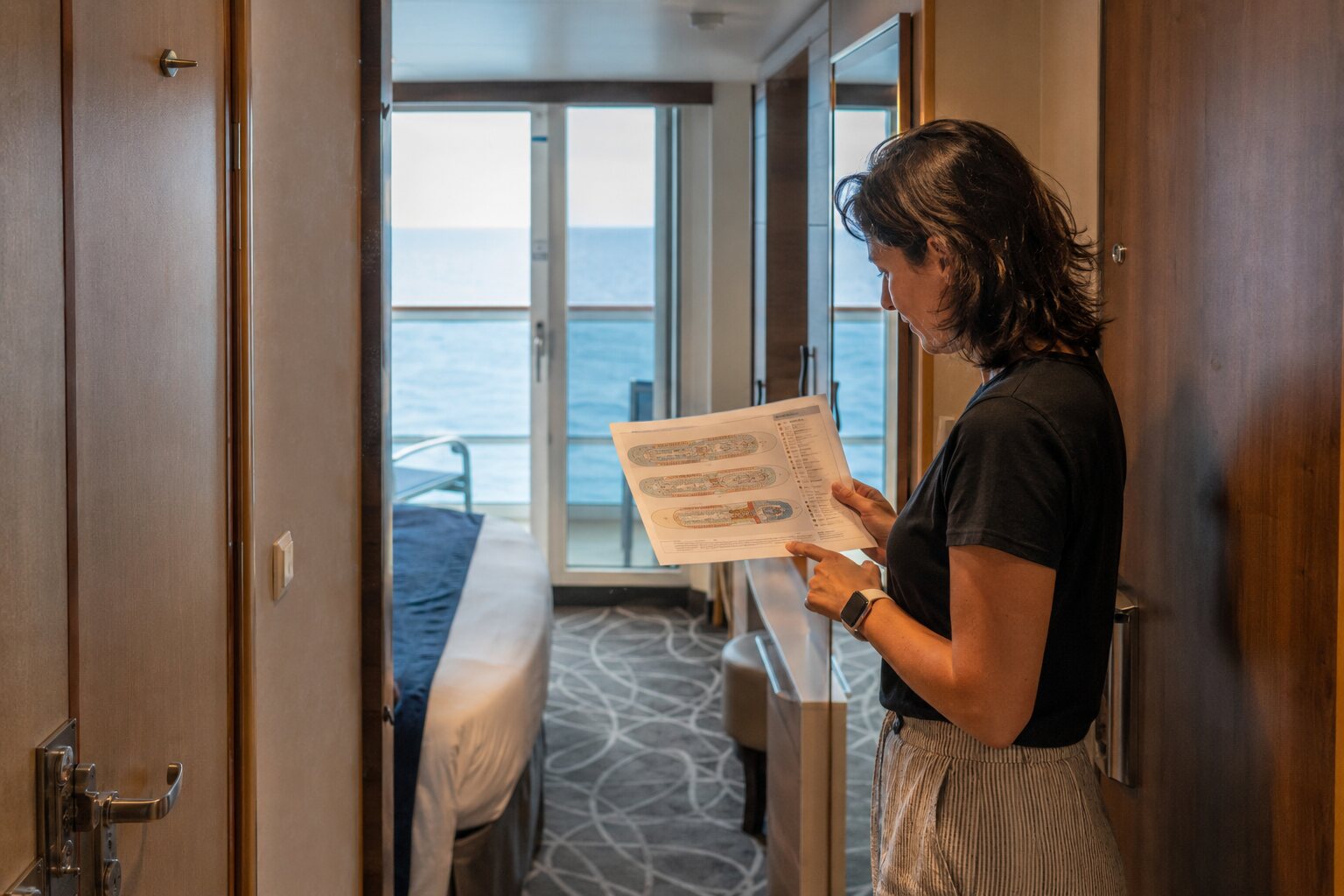 Traveler checking a cruise ship deck plan inside a balcony cabin