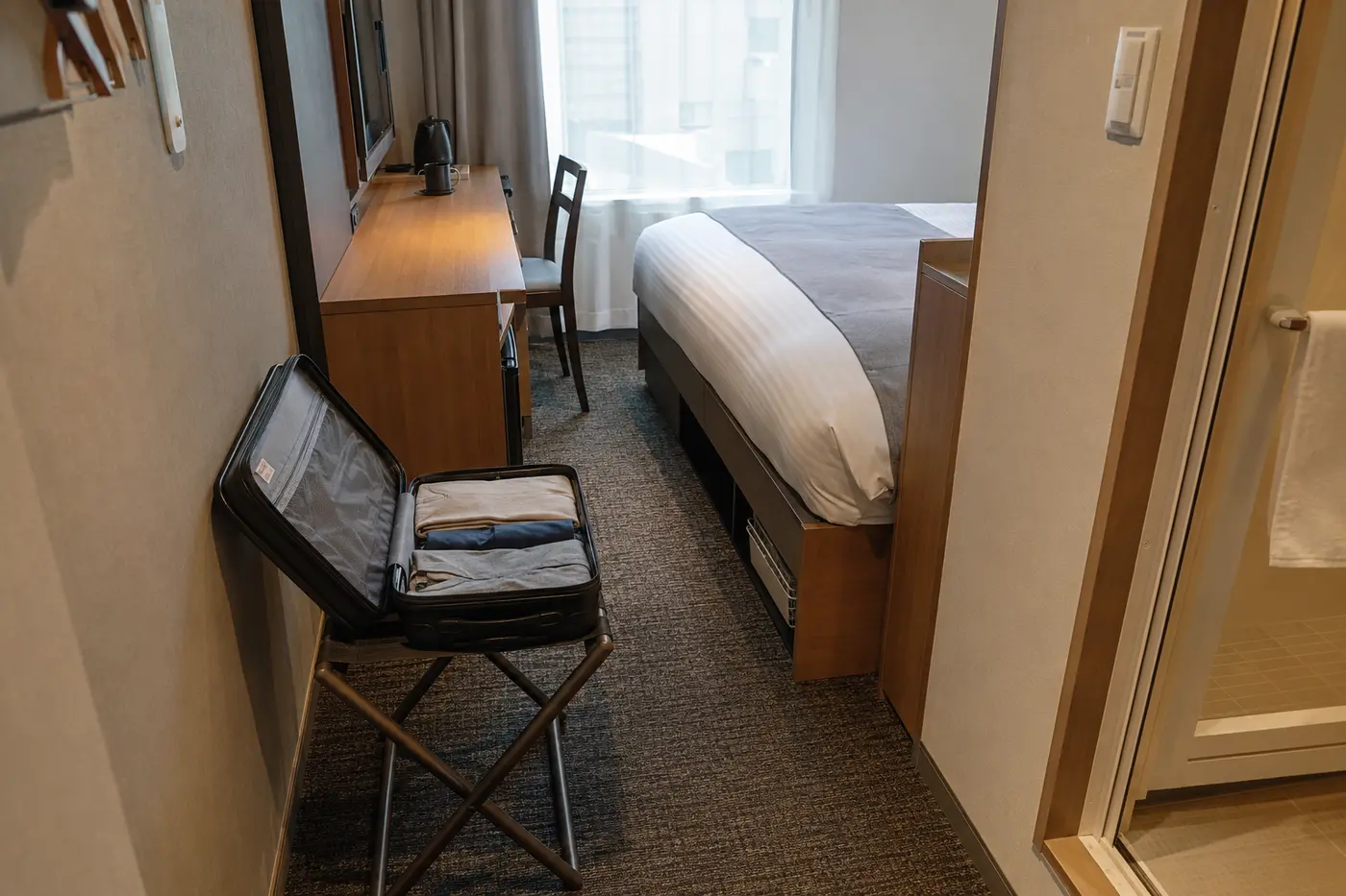Compact Tokyo hotel room with an open suitcase on a luggage rack