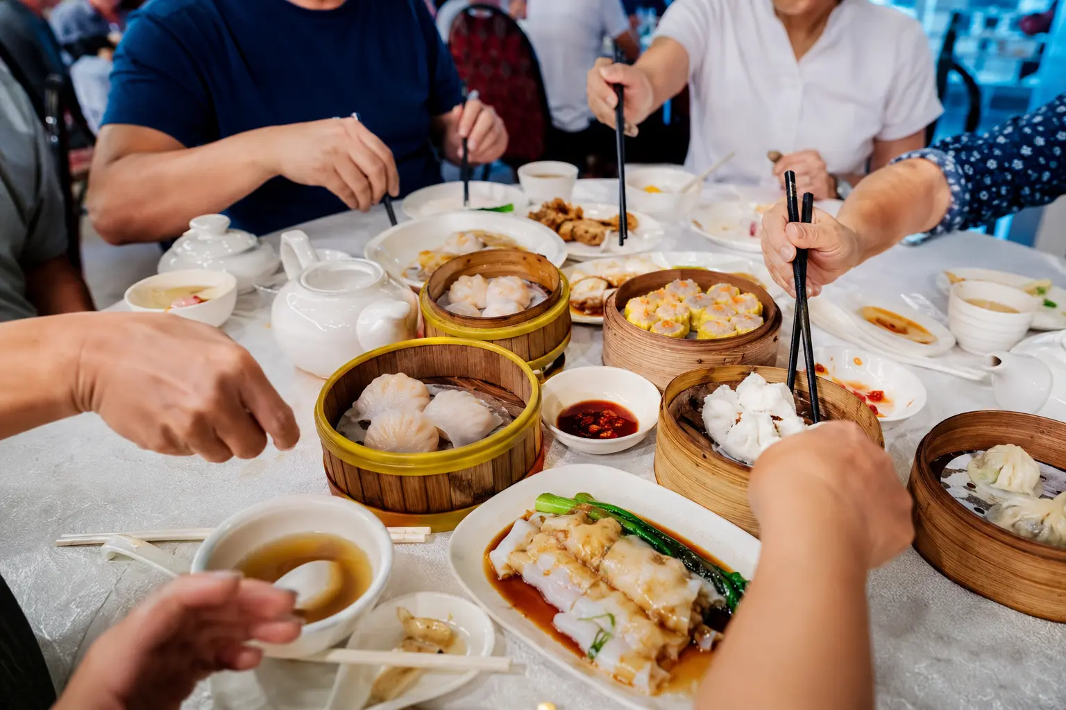 Diners sharing bamboo steamers of dim sum around a Hong Kong lunch table