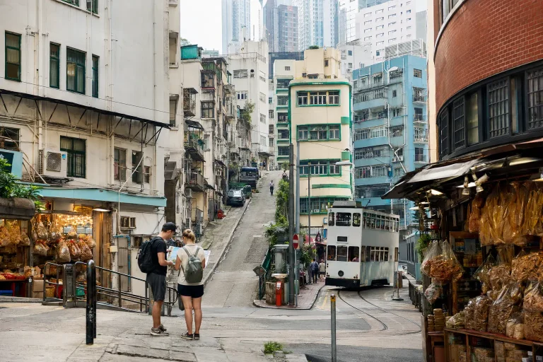 Travelers choosing a walking route among steep lanes, shops and a tram in Sheung Wan, Hong Kong