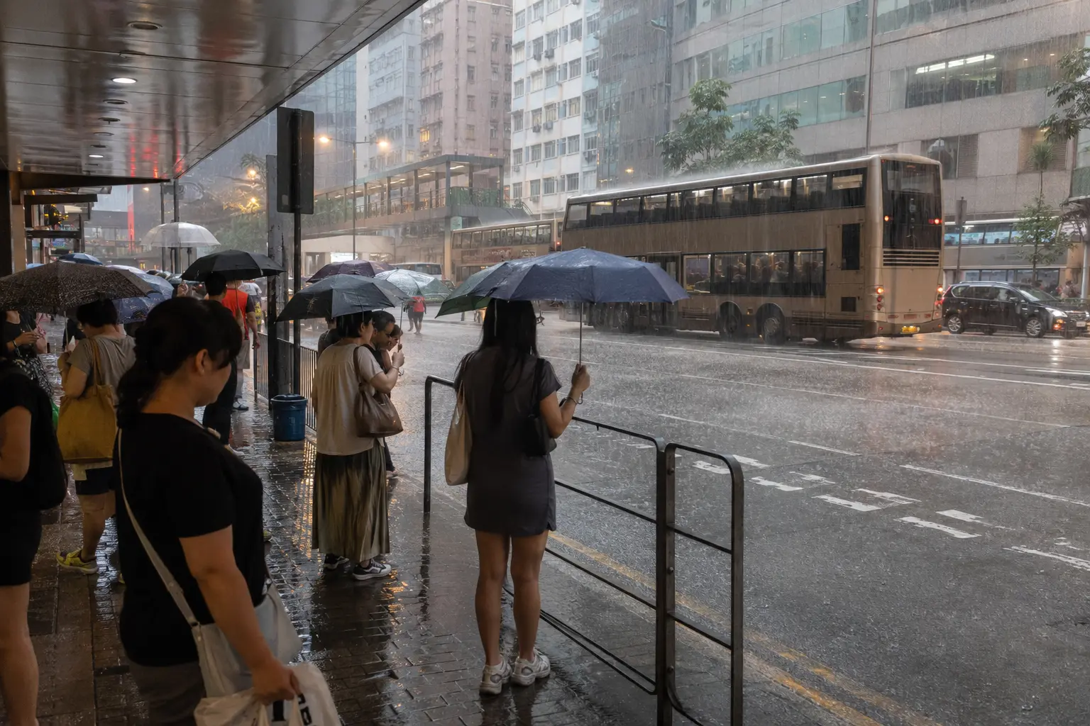 People sheltering under a covered walkway during heavy summer rain in Hong Kong