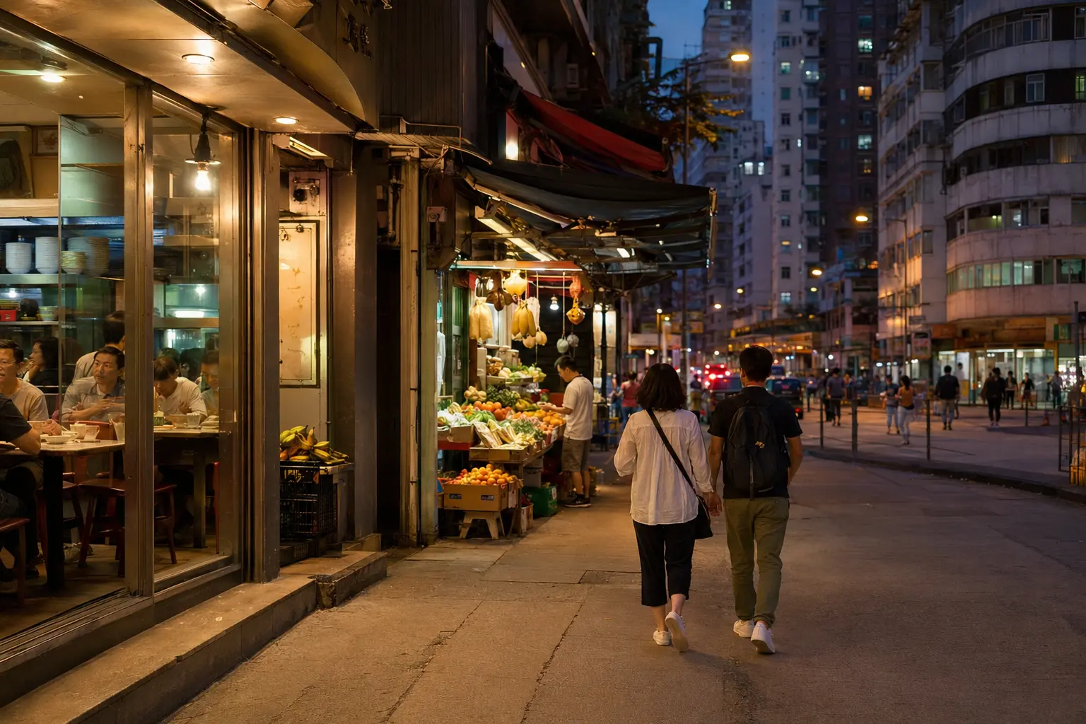 Travelers walking past a restaurant and fruit stall in Jordan after dark