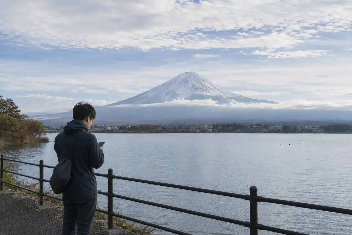 Traveler checking the weather beside Lake Kawaguchiko with Mount Fuji partly clouded