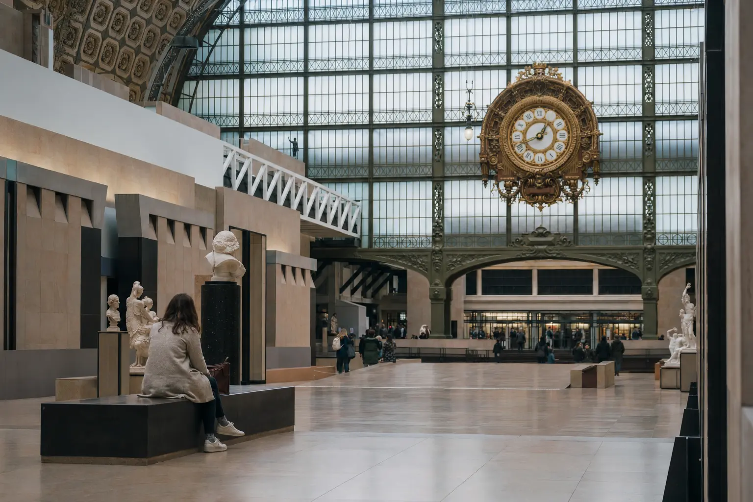 Visitor resting on a bench beneath the large clock inside the Musée d’Orsay