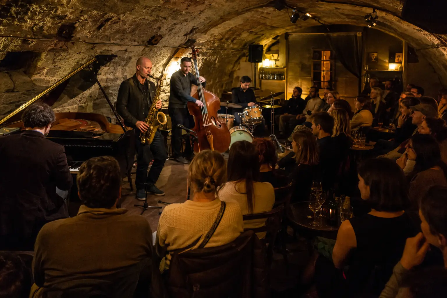 Jazz quartet performing for a seated audience in a Paris cellar club