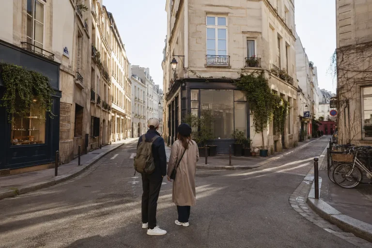 Two travelers choosing a walking route at a quiet intersection in the Marais