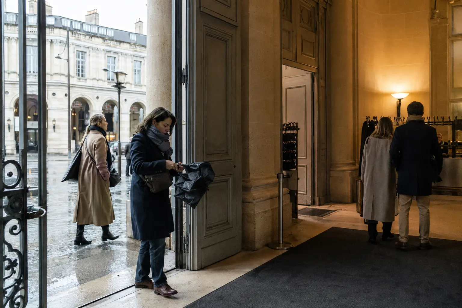 Visitors folding a wet umbrella as they enter a Paris museum on a winter day