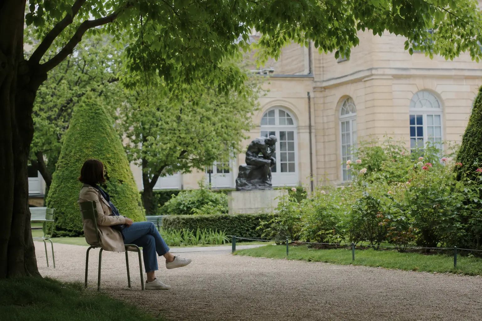 Visitor seated in the shaded sculpture garden at the Rodin Museum in Paris