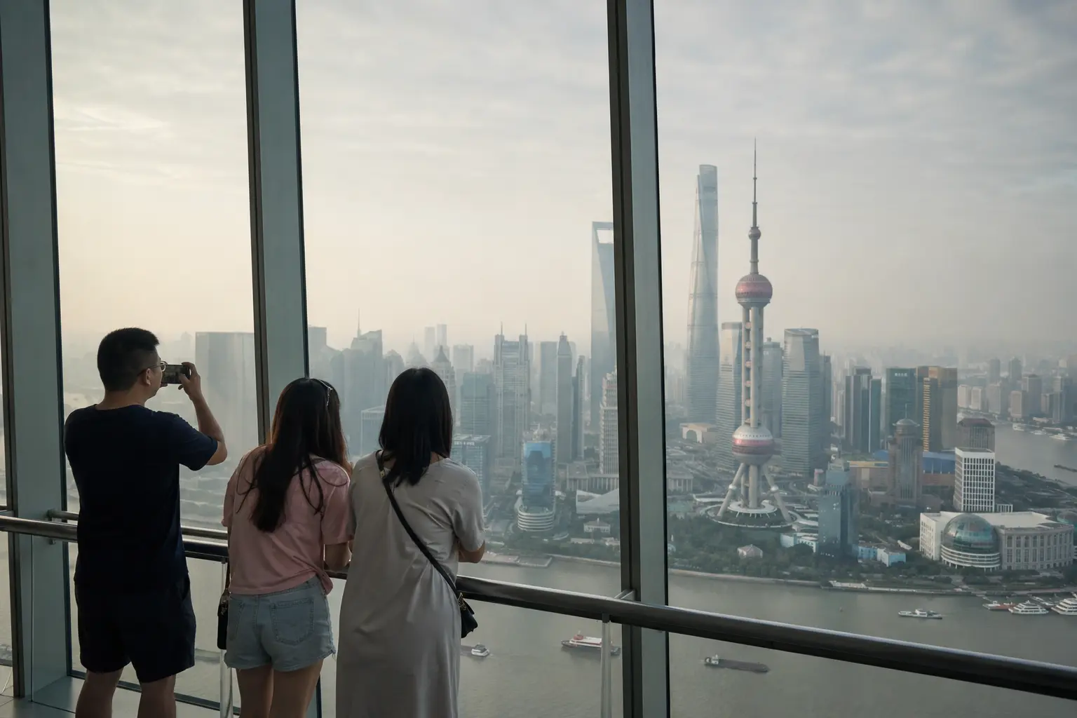 Visitors viewing the Shanghai skyline through light haze from an observation deck