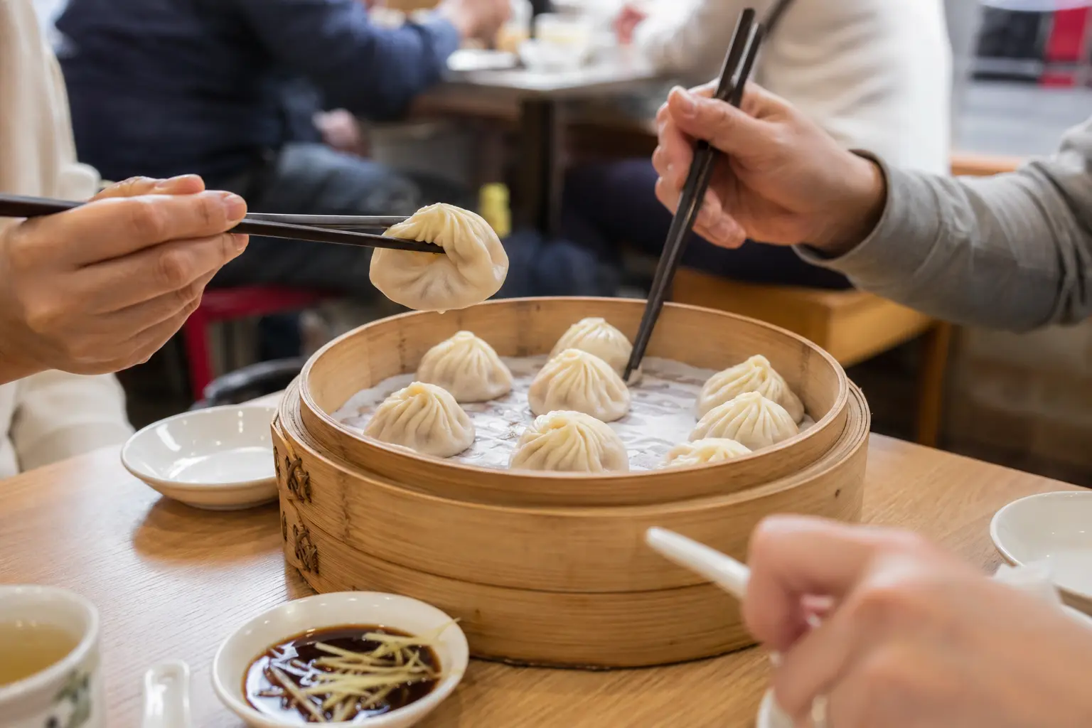 Diners sharing Shanghai xiaolongbao with vinegar and ginger