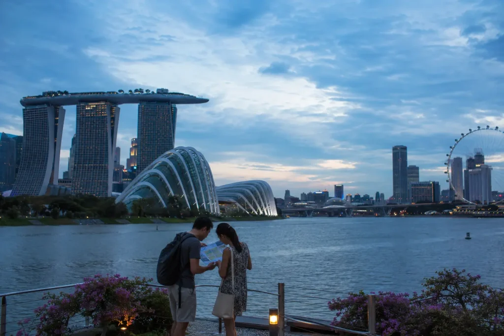 Travelers planning a Singapore itinerary beside Marina Bay at dusk