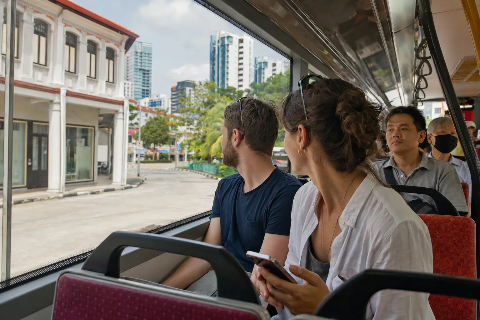 Travelers viewing Singapore neighborhoods from a public bus