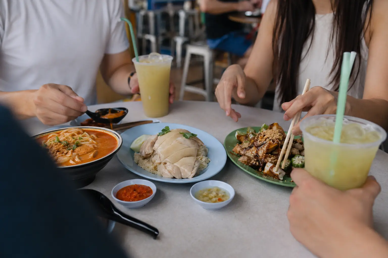 Diners sharing several Singapore hawker dishes