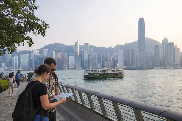 Travelers planning things to do in Hong Kong beside Victoria Harbour and a Star Ferry
