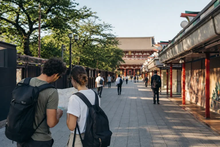 Two travelers checking a map on a quiet morning approach to Senso-ji in Tokyo