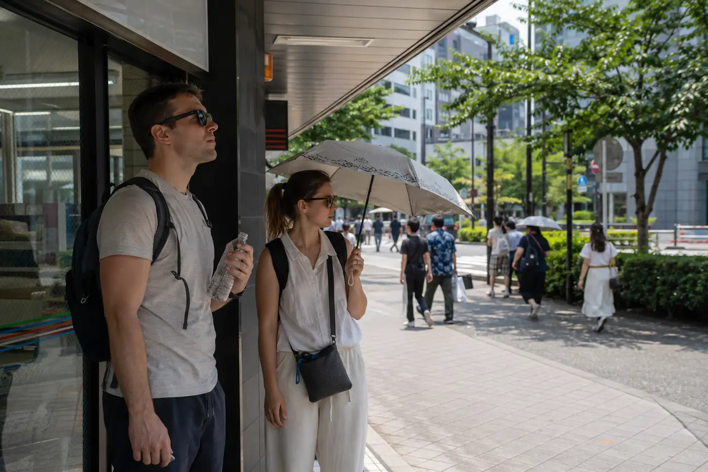 Travelers pausing in shade with water and a parasol during hot Tokyo summer weather