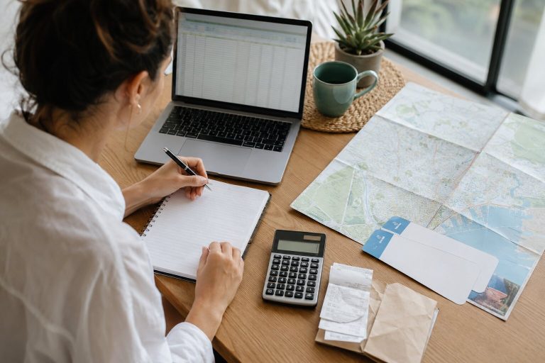 Traveler building a travel budget spreadsheet beside a map and receipts