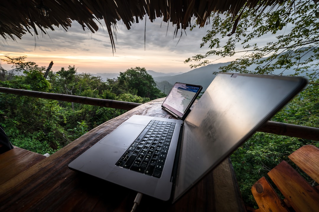 Laptop and phone on a wooden table with mountain view — The Complete Guide to Digital Nomad Visas: Compare 12+ Countries