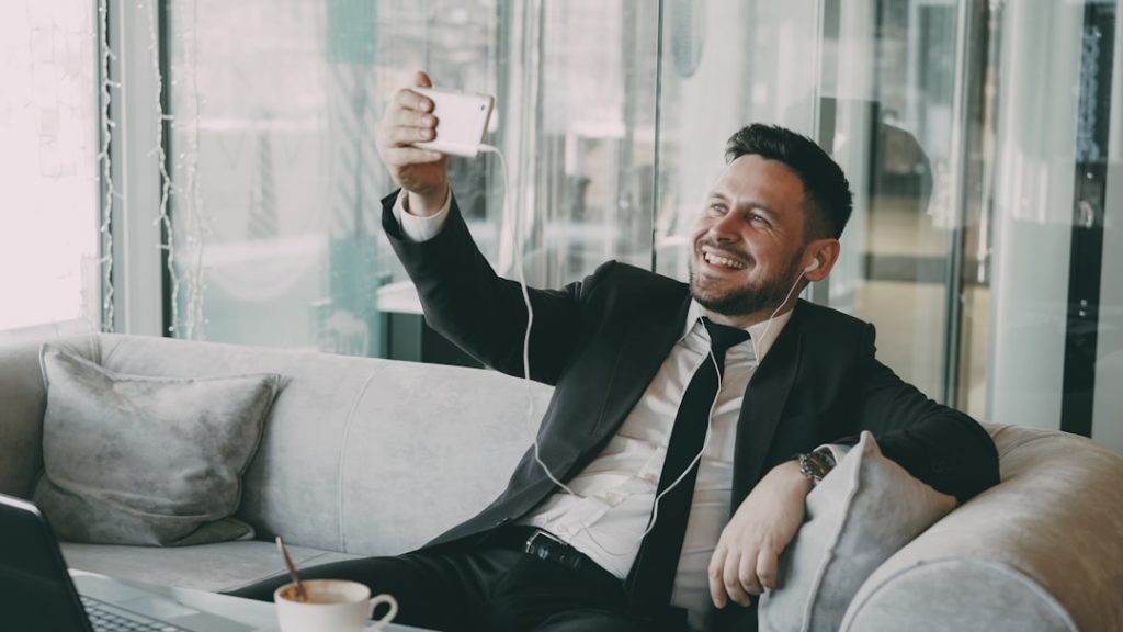 Cheerful Caucasian businessman in formal clothes having online video call with smartphone webcam in modern cafe. — the complete guide to digital nomad visa