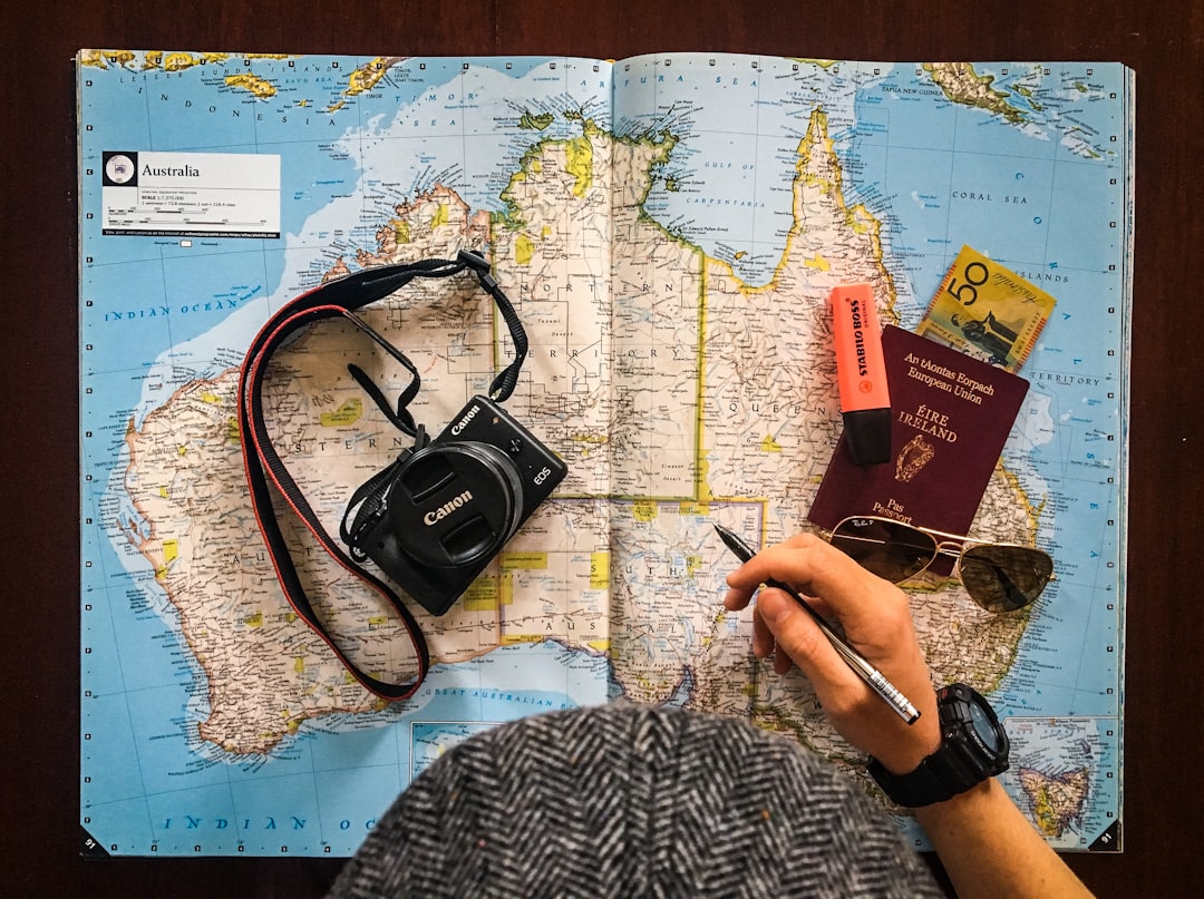 flat lay photography of person holding pen in front of world map — Digital Nomad Health Insurance: What Actually Works in 2026