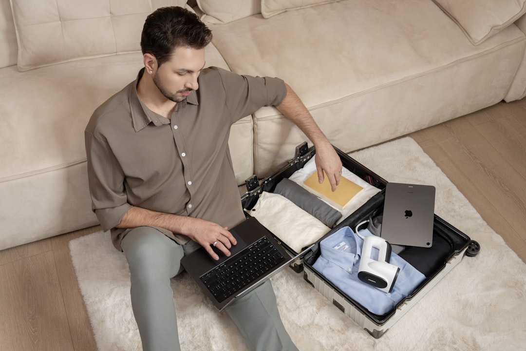 A man packs his suitcase with clothing, a book, and a vacuum steamer. — Digital Nomad Productivity Tips That Actually Work