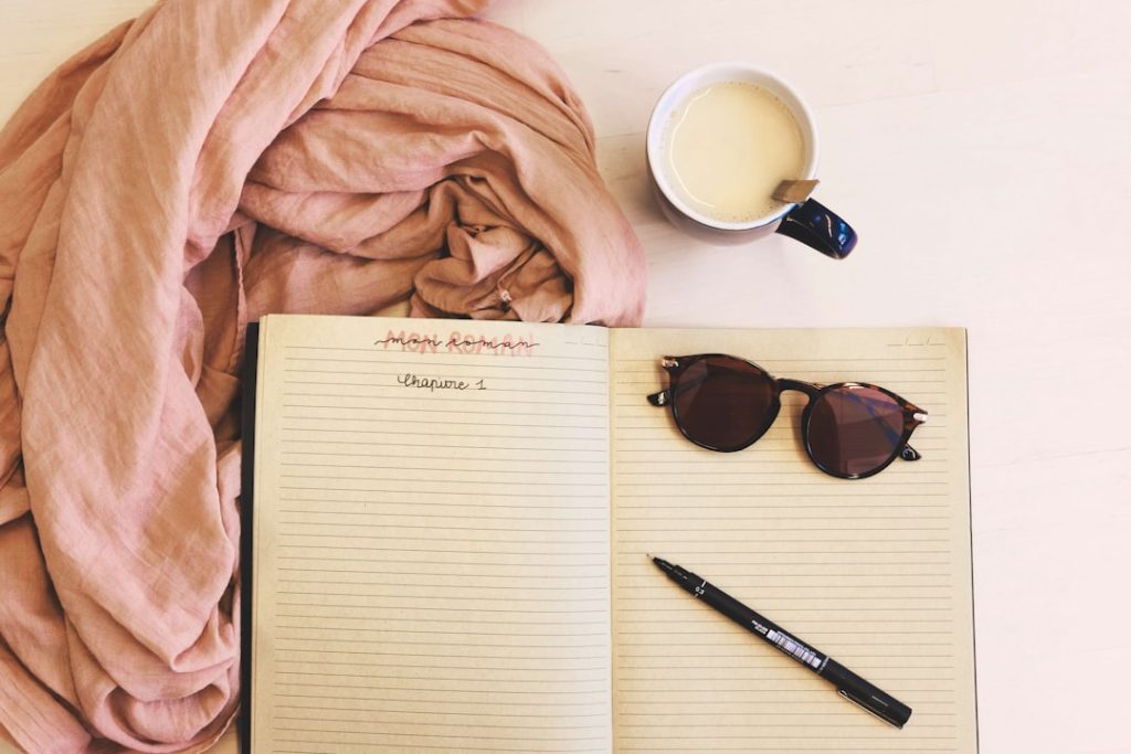 ballpoint pen and sunglasses on opened notebook — morning journal prompts