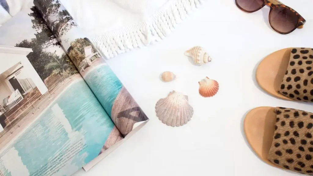 Beach towel, sandals, sunglasses and seashells laid out for a vacation