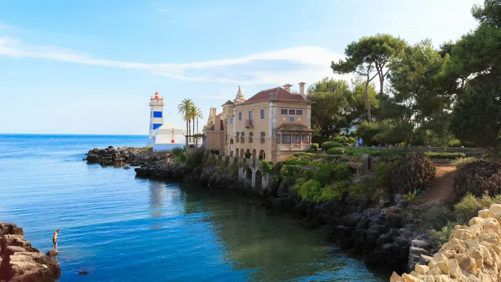 Lighthouse and historic waterfront buildings beside the rocky Cascais coast