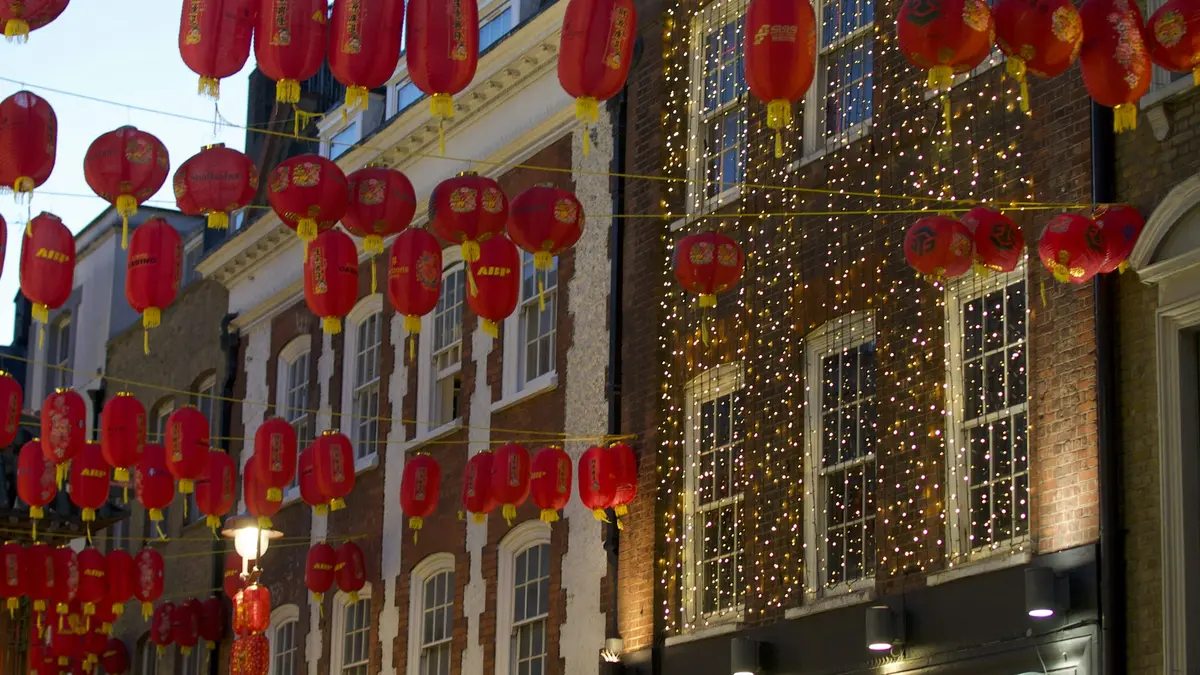 People walking beneath red lanterns in London's Chinatown at night