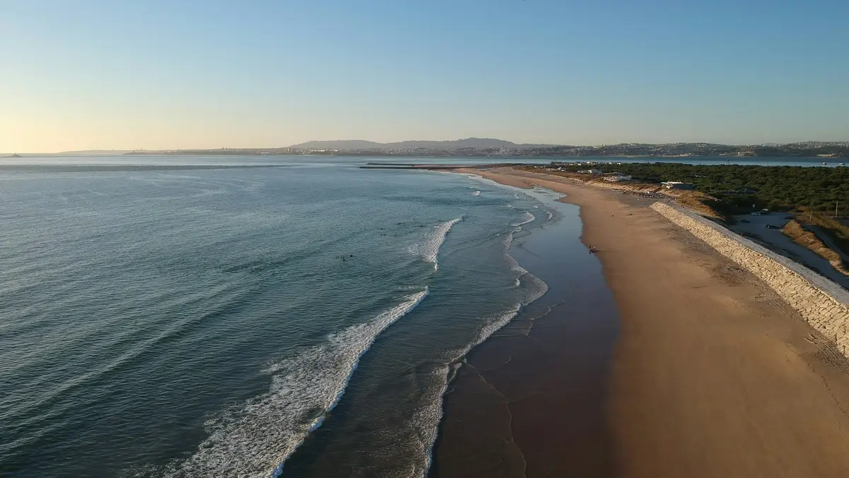 Aerial view of a broad sandy beach and Atlantic waves at Costa da Caparica
