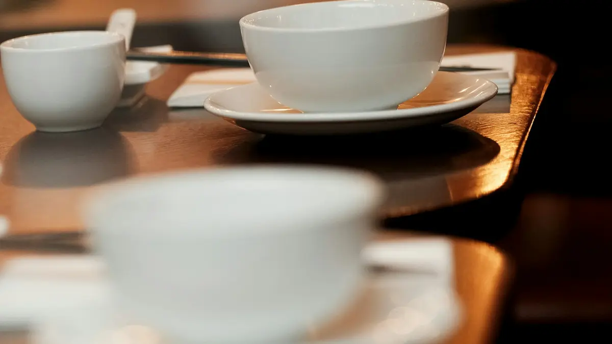 White bowls, saucers and chopsticks on a reflective cafe table in Covent Garden