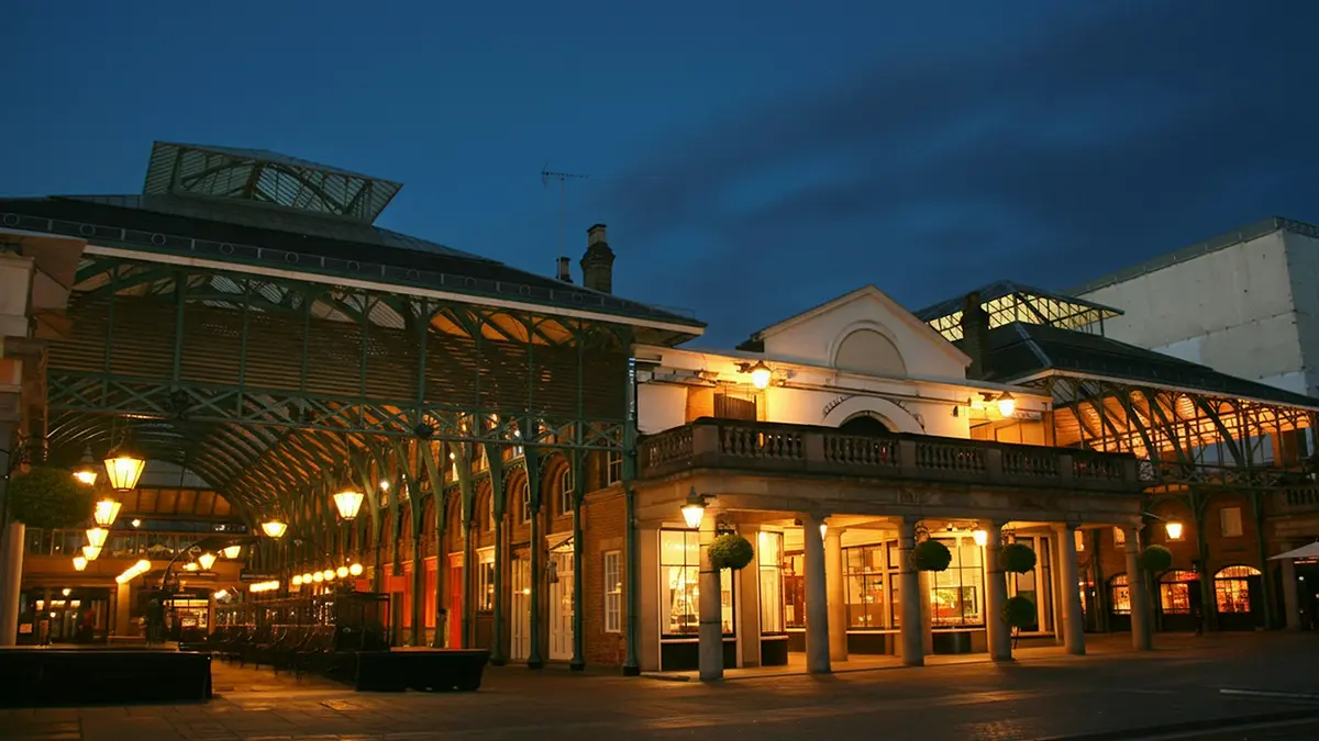 Illuminated iron-and-glass halls of Covent Garden Market at dusk