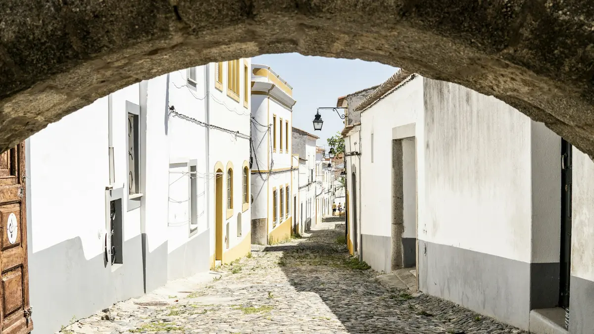 Narrow cobblestone street between whitewashed buildings in Évora