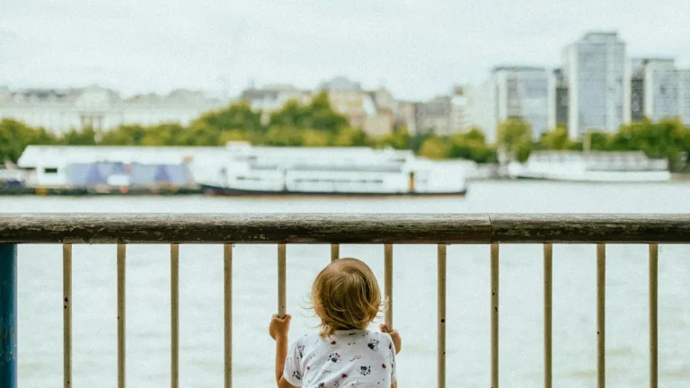 Child standing by a railing during a family walk beside the Thames in London
