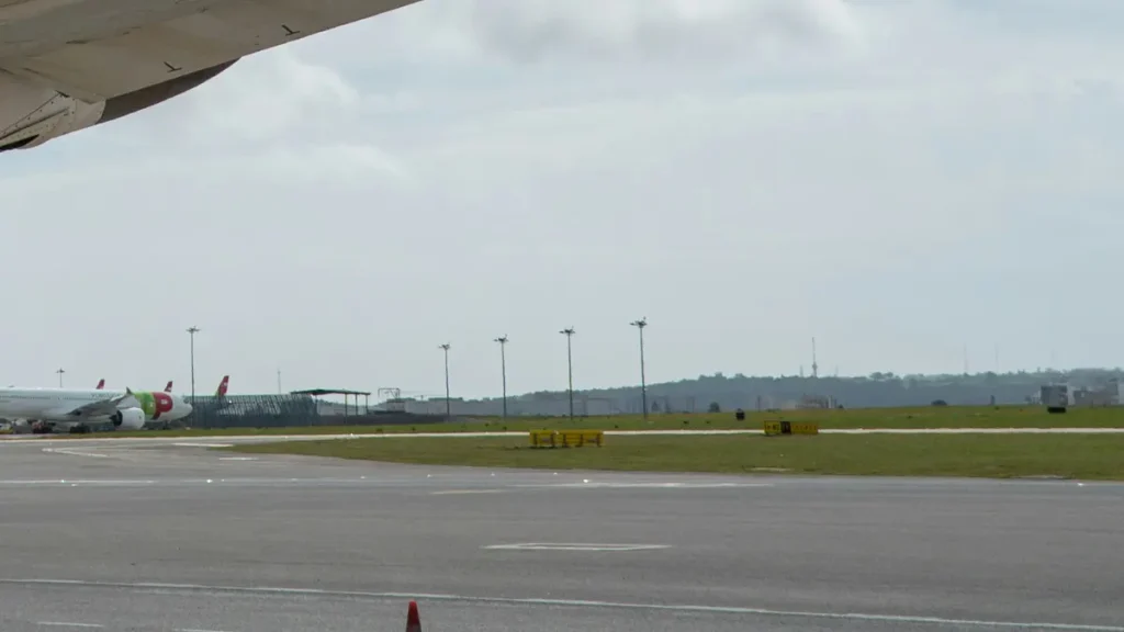 Aircraft wing above the runway and distant parked planes at Humberto Delgado Airport in Lisbon