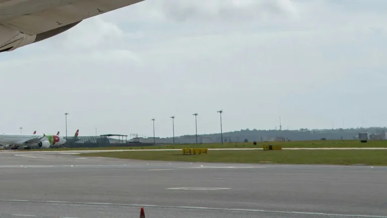 Aircraft wing above the runway and distant parked planes at Humberto Delgado Airport in Lisbon