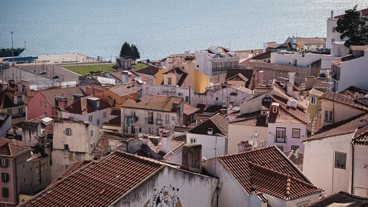 Terracotta rooftops in Alfama descending toward the Tagus River in Lisbon