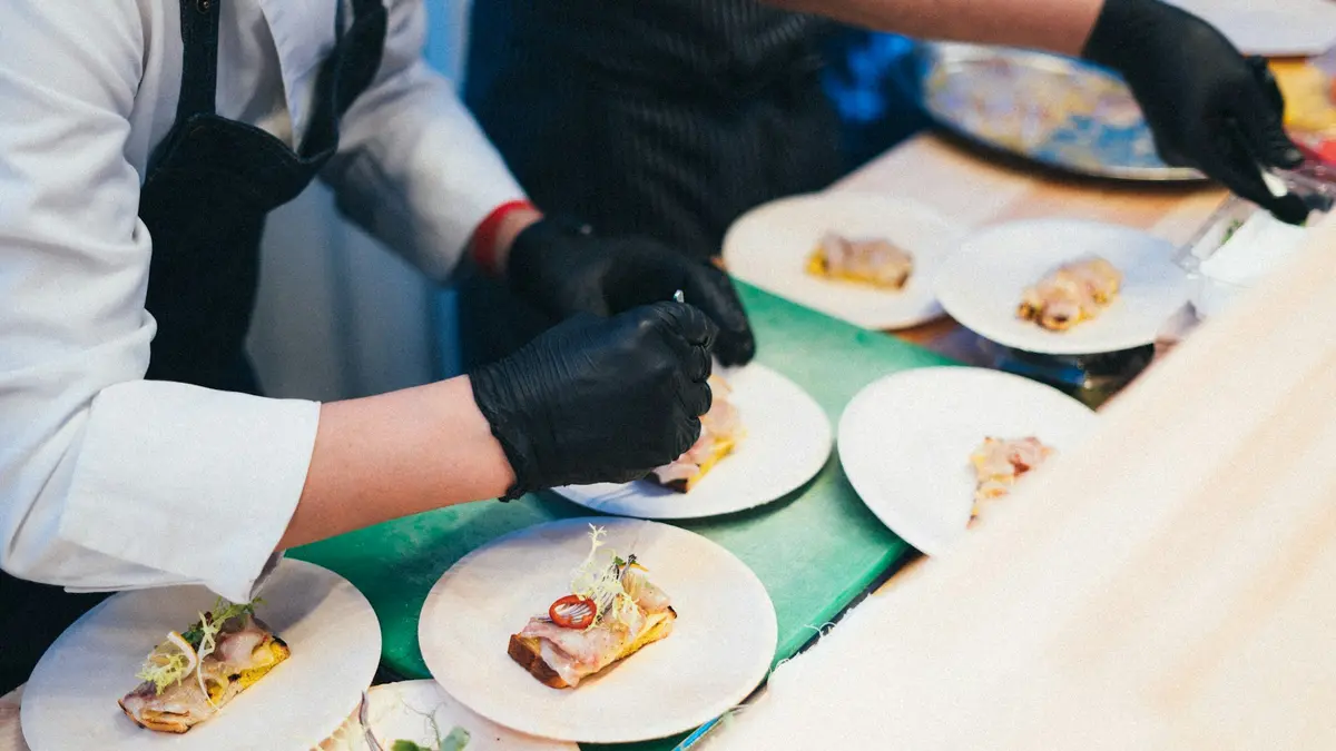 Gloved chefs arranging small plated dishes on a kitchen counter in Lisbon
