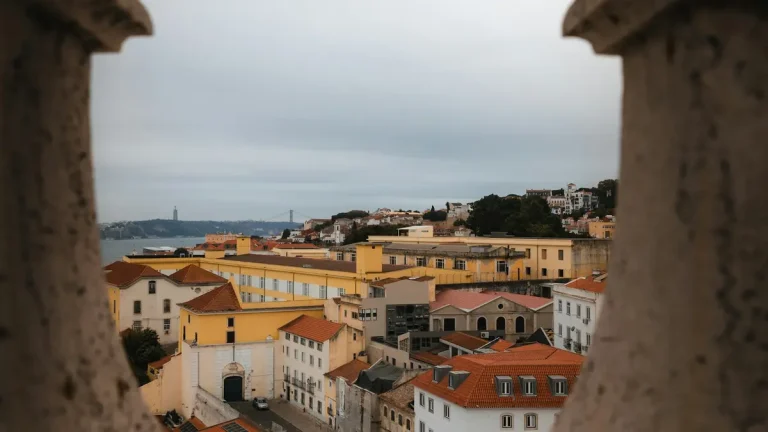 Lisbon rooftops and waterfront framed by weathered stone arches