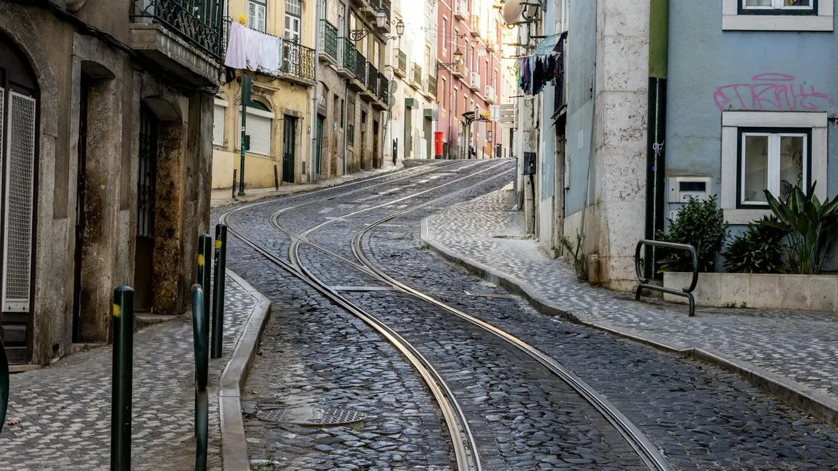 Curving tram tracks and pedestrian pavements on an empty cobblestone street in Lisbon