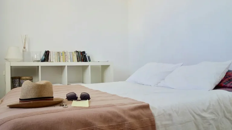 Simple Lisbon guest room with a double bed, white pillows, bookshelf, hat and sunglasses