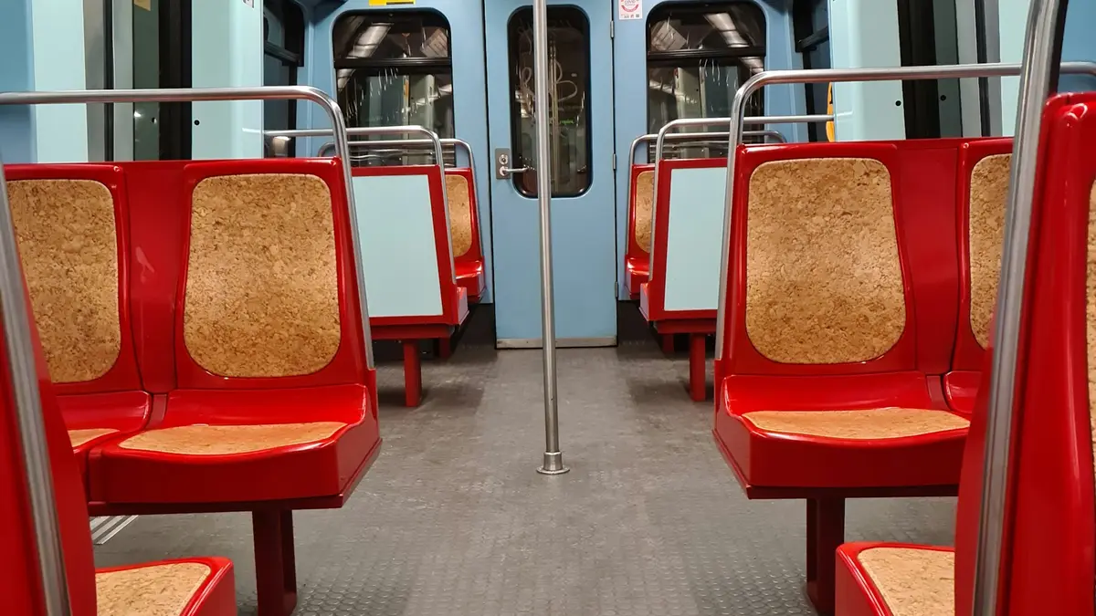 Empty Lisbon Metro car with red seats, pale blue doors and metal handrails