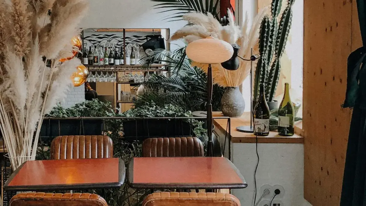 Intimate Lisbon restaurant interior with vintage chairs, plants, and wine bottles