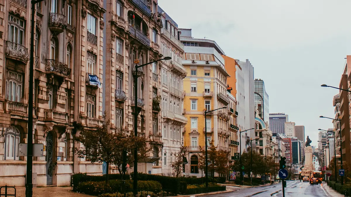 Wet Lisbon avenue under an overcast sky, lined with historic buildings