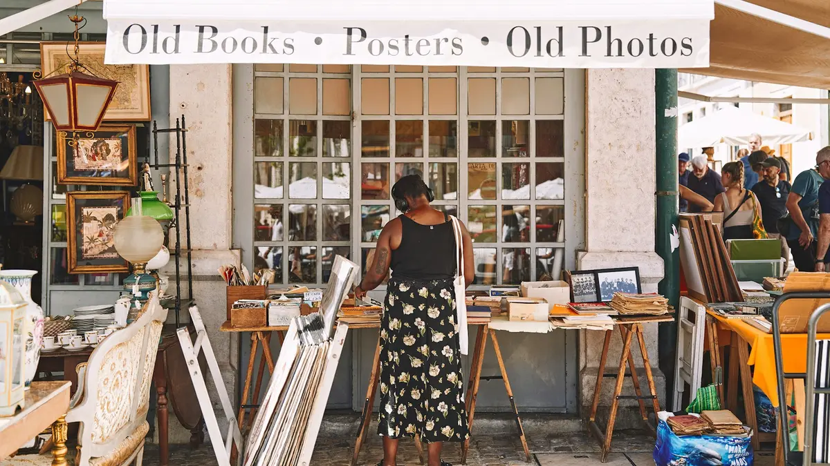 Shopper seen from behind browsing books and old photographs at Mercado de Santa Clara in Lisbon