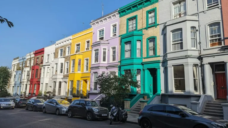 Colorful terraced houses and parked cars on a sunny residential street in Notting Hill