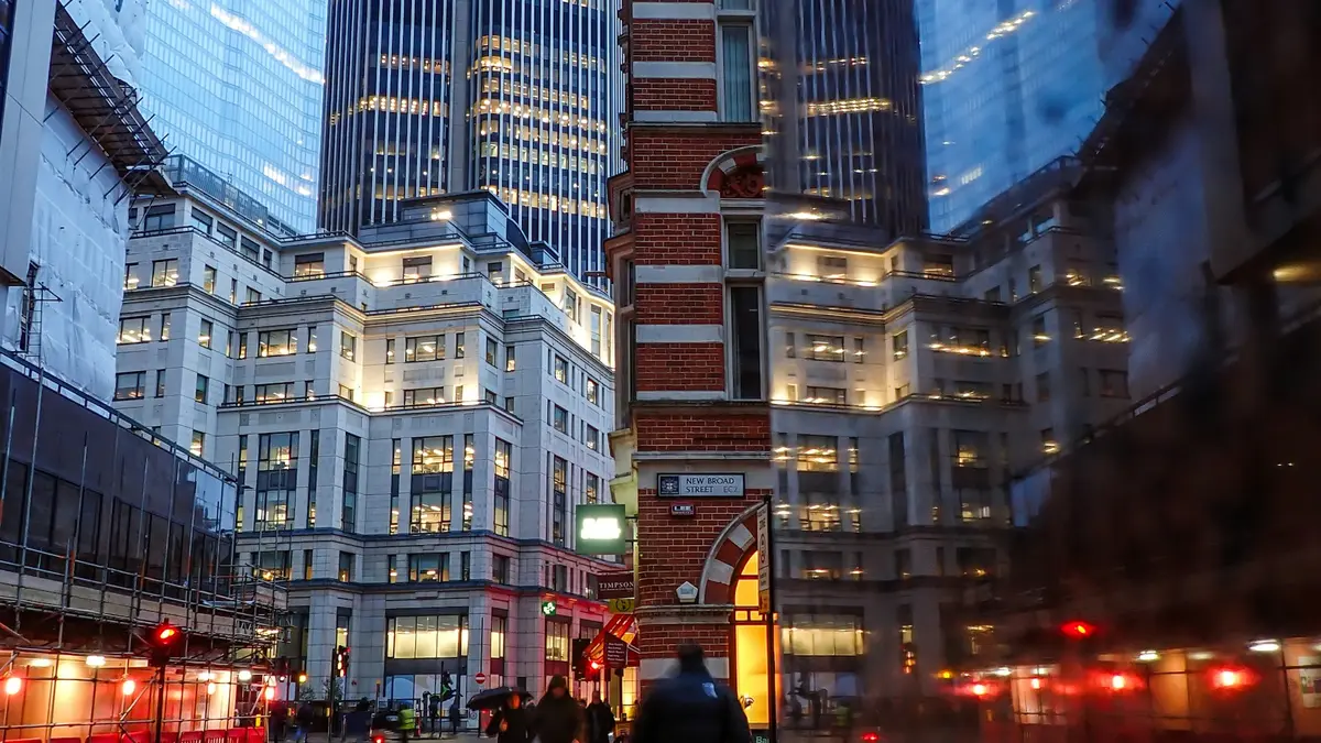 Rain-softened view of illuminated office buildings and pedestrians near New Broad Street in the City of London