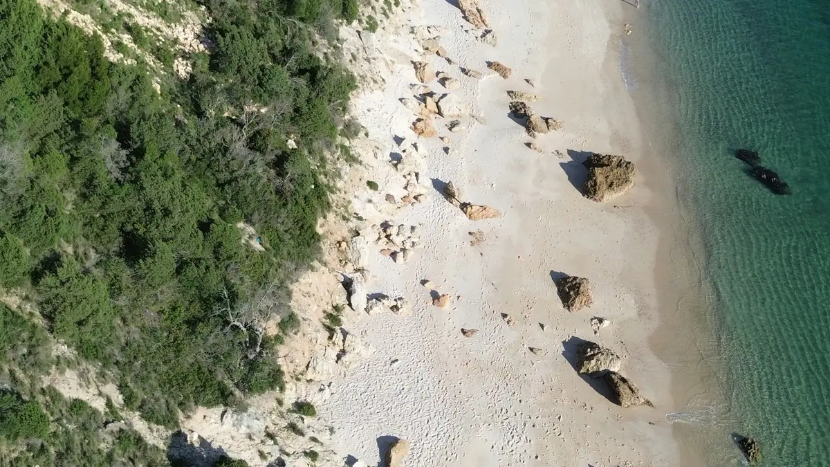 Aerial view of a sandy cove and clear blue water at Portinho da Arrábida