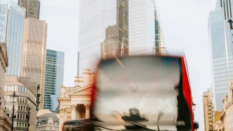 Motion-blurred red double-decker bus passing modern buildings in London's Bank district